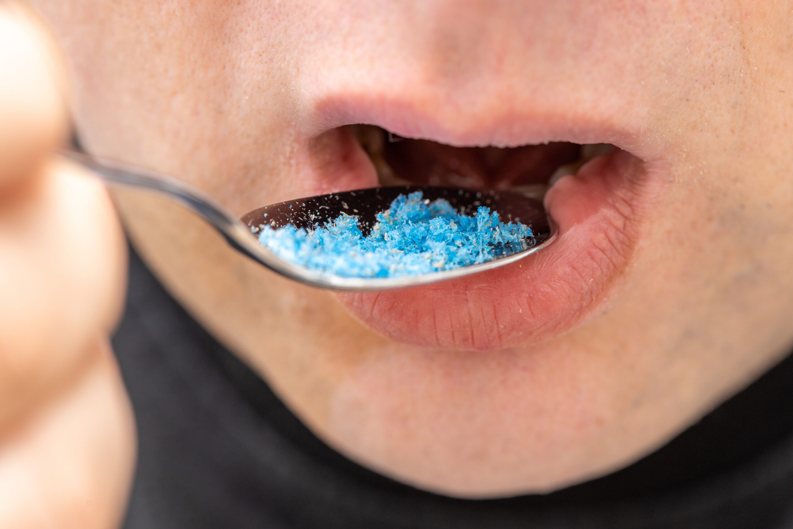 Person eating microplastics from a spoon — microplastic pollution from synthetic clothing entering the human body